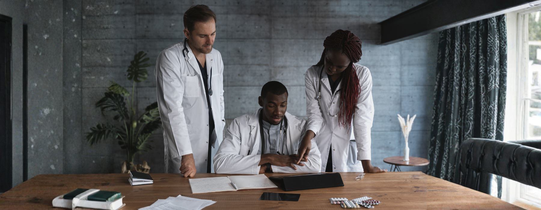 three medical practitioners looking at papers on a table